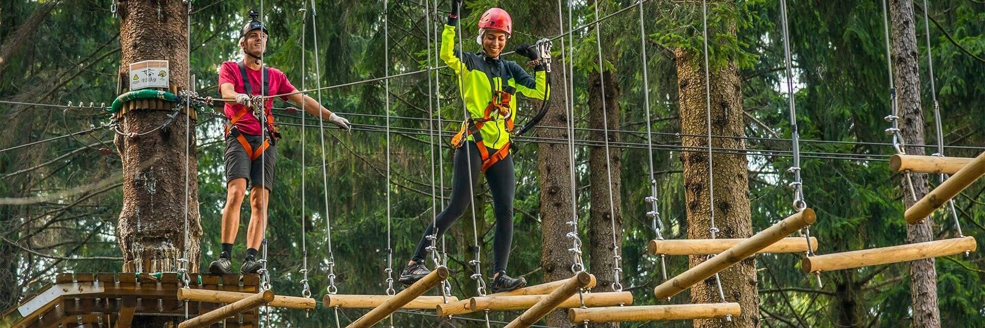 Delle persone si divertono al parco avventura affrontando un percorso sugli alberi